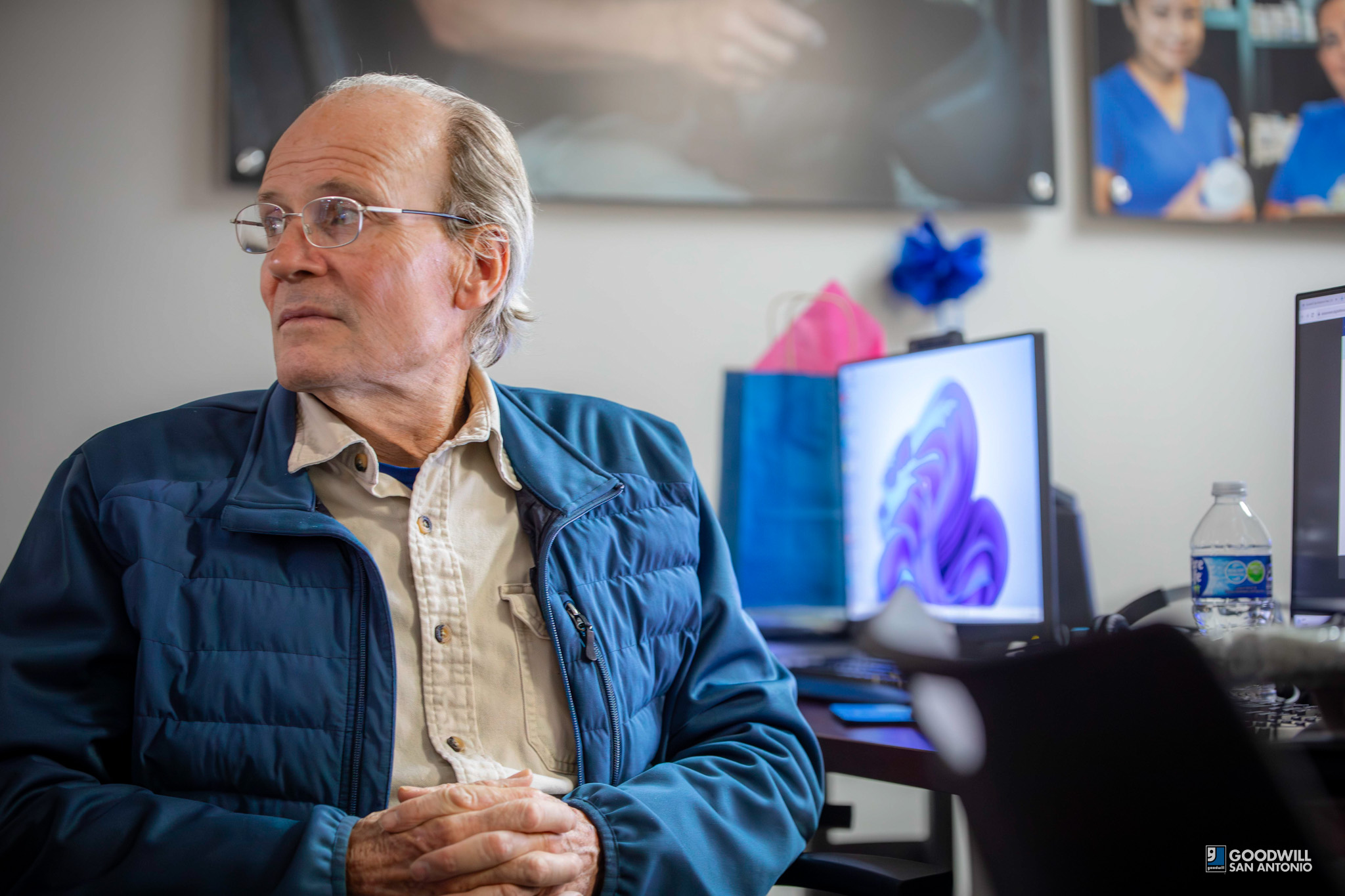 Len McClure, Goodwill San Antonio Digital Literacy Student. Male, glasses, blue jacket in front of computer