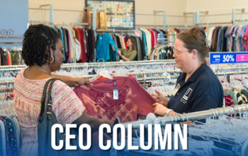 Goodwill San Antonio team member and shopper look at pink blouse.